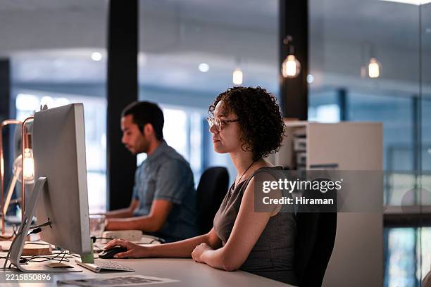modern office environment with professionals focused on computer tasks - low lighting stock pictures, royalty-free photos & images