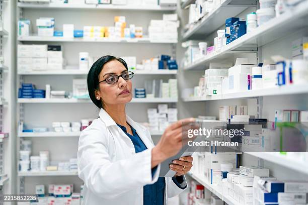 farmacéutico experimentado que organiza los estantes en un entorno farmacéutico moderno - material médico fotografías e imágenes de stock