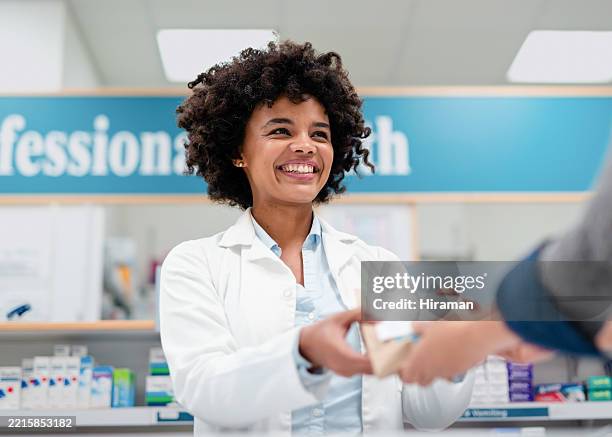 smiling pharmacist assisting customer at modern pharmacy counter, friendly healthcare service - pharmacist stock pictures, royalty-free photos & images