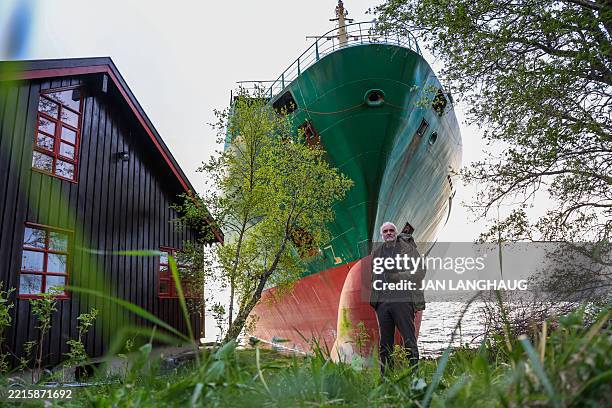 Johan Helberg poses next to his house and a 135-meter-long container ship by the shore in the Trondheimsfjord outside Byneset by Trondheim, Norway,...