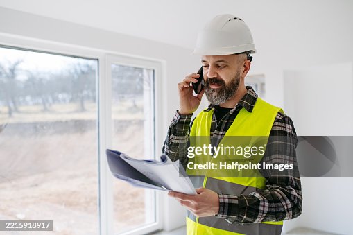 Construction manager making phone call while inspecting progress on building site. Construction manager making phone call while inspecting progress on building site.