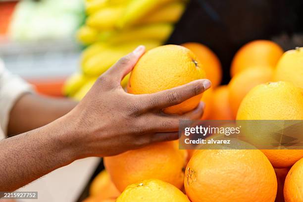 close-up of man buying oranges from grocery store - picking up groceries stock pictures, royalty-free photos & images