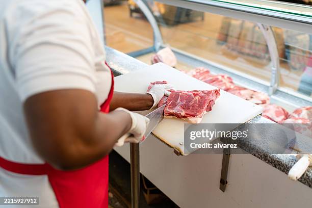 primer plano de la mujer cortando carne roja en una tabla de cortar blanca en una tienda - carnicero fotografías e imágenes de stock