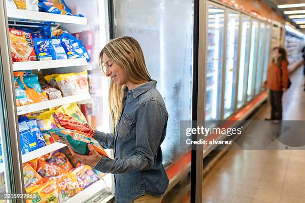 une femme choisit des aliments surgelés à l’épicerie du supermarché - aliment surgelé photos et images de collection