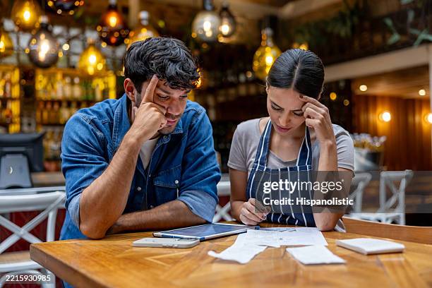owner and waitress doing the accountancy at a restaurant and looking worried - bookkeeping stock pictures, royalty-free photos & images