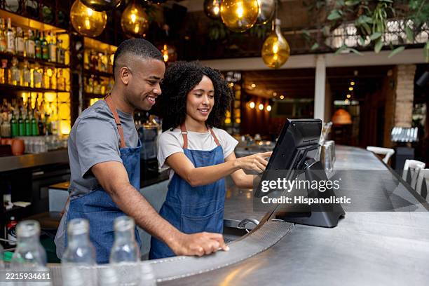 camarera entrenando a un nuevo empleado mientras trabaja en un restaurante - camarero fotografías e imágenes de stock