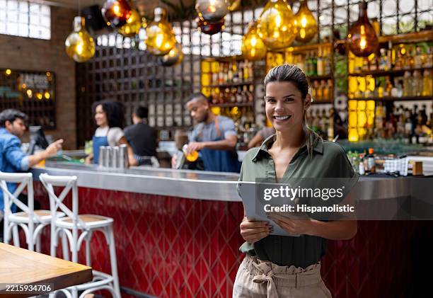 happy business manager smiling at a restaurant and holding a tablet - party host stock pictures, royalty-free photos & images