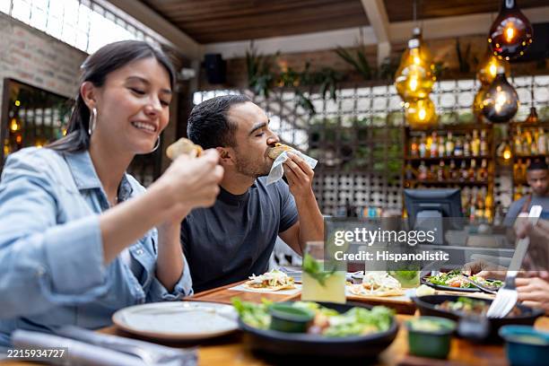 happy friends eating while having dinner at a restaurant - foodie stockfoto's en -beelden
