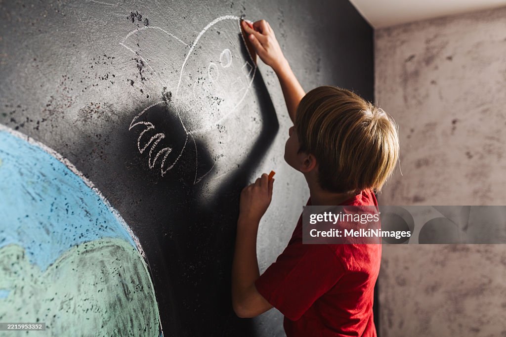 Boy Drawing Space Adventure on Chalkboardpr