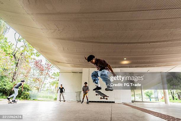 junger mann macht skateboard-trick im öffentlichen park - extreme skateboarding stock-fotos und bilder