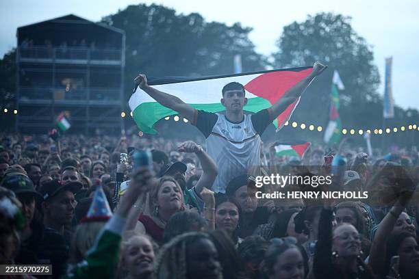 Festivalgoers hold Palestine flags as they wait to hear Northern Irish Hip Hop trio Kneecap perform onstage during Wide Awake Festival 2025 at...