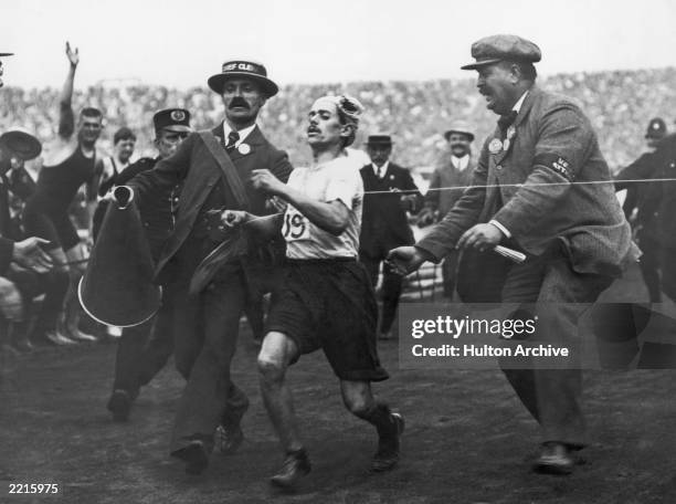 Dorando Pietri of Italy, on the verge of collapse, is helped across the finish line in the Marathon event of the Olympic Games in London, 24th July...