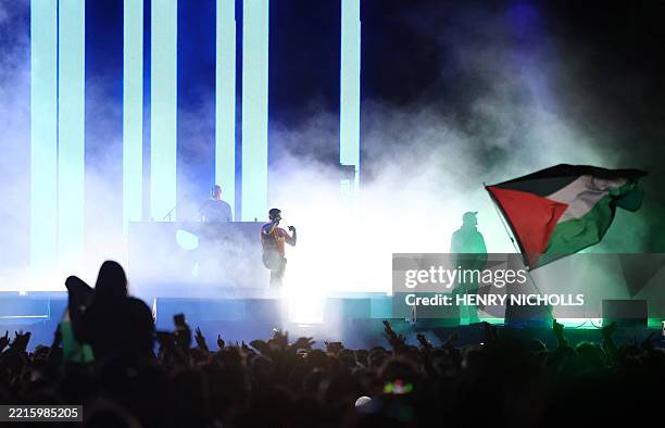 Festivalgoers fly a Palestine flag as Liam O'Hanna, aka Mo Chara from Northern Irish Hip Hop trio Kneecap performs with bandmates Naoise O...