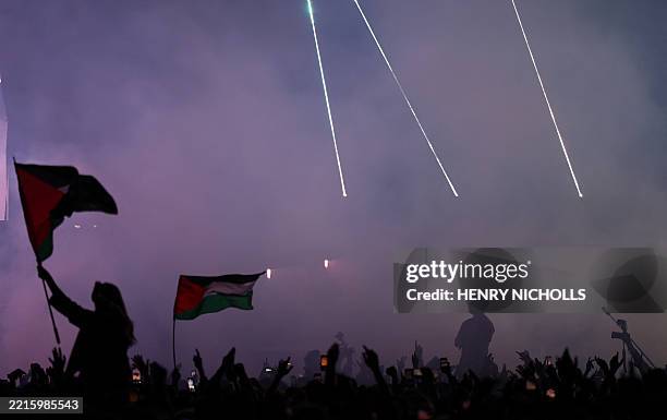Festivalgoers fly a Palestine flag as Liam O'Hanna, aka Mo Chara from Northern Irish Hip Hop trio Kneecap performs with bandmates Naoise O...