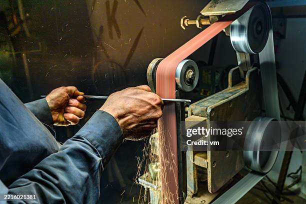 skilled craftsman operating belt grinder with sparks flying in workshop environment - belt stock pictures, royalty-free photos & images