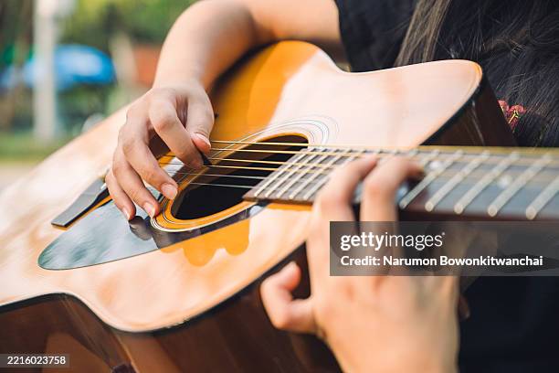 young woman relaxing and playing guitar outdoors in nature - akustikgitarre stock-fotos und bilder
