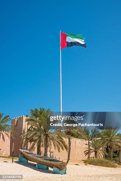 uae flag over historic fort and boat - flagpole stock pictures, royalty-free photos & images