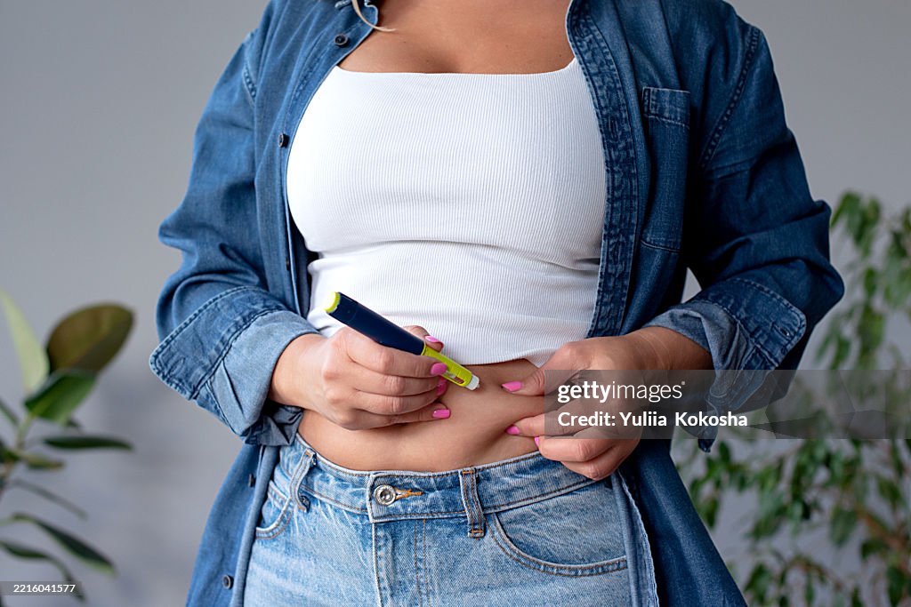 Woman suffering from sugar diabetes giving insulin injection at home using diabetic pen
