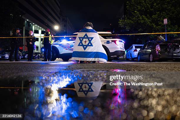Bystander prays while wearing an Israel flag with a cross in the middle, near the Capital Jewish Museum near the U.S. Capitol on May 21, 2025 in...