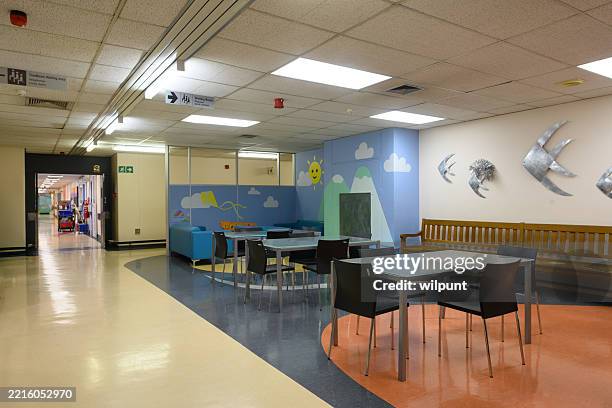 brightly decorated hospital pediatric waiting area with seating and colorful wall art - childrens hospital stock pictures, royalty-free photos & images