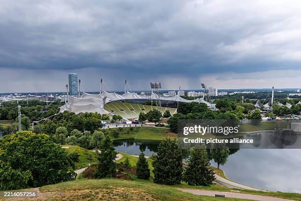 May 2025, Bavaria, Munich: The Olympic grounds in the Olympic Park with the Olympic Stadium in Munich . The O2 Tower can be seen in the background....