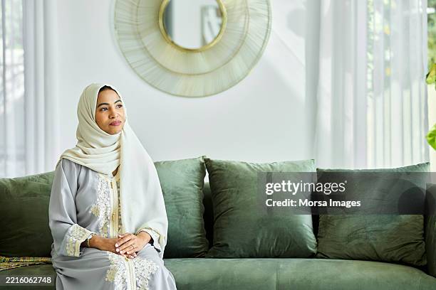 emirati woman day dreaming on sofa at home - modest clothing stock pictures, royalty-free photos & images
