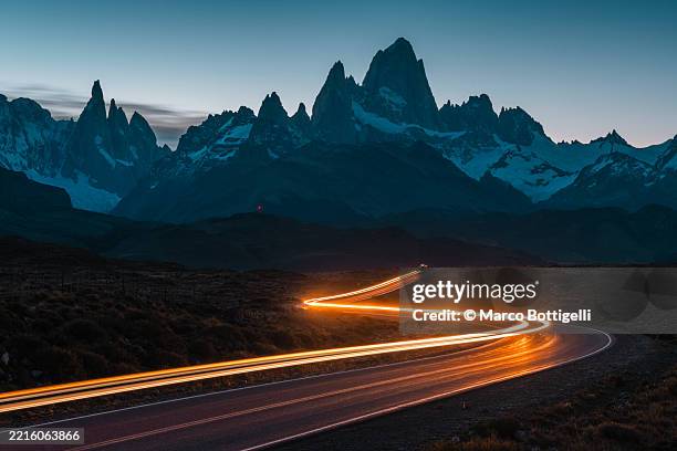 silhouetted mt fitz roy with winding road and light streaks at dusk, patagonia, argentina - light trail imagens e fotografias de stock
