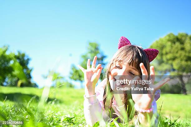playful child sticking out tongue lying in grass on sunny day - cat costume stock pictures, royalty-free photos & images