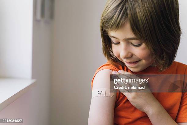 young boy admiring her vaccination band-aid - vacina imagens e fotografias de stock