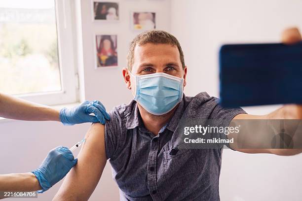 man getting vaccinated while taking a selfie - vaxxie stock pictures, royalty-free photos & images