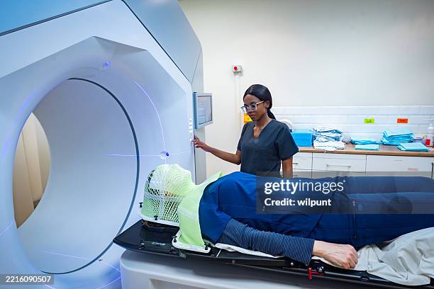 medical professional assisting a radiotherapy patient during treatment session - radiação imagens e fotografias de stock