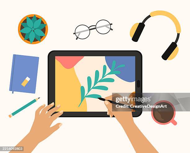 hands drawing on a digital tablet. high angle view of desk with wireless headphones, notepad, eyeglasses and coffee cup - graphic designer stock illustrations