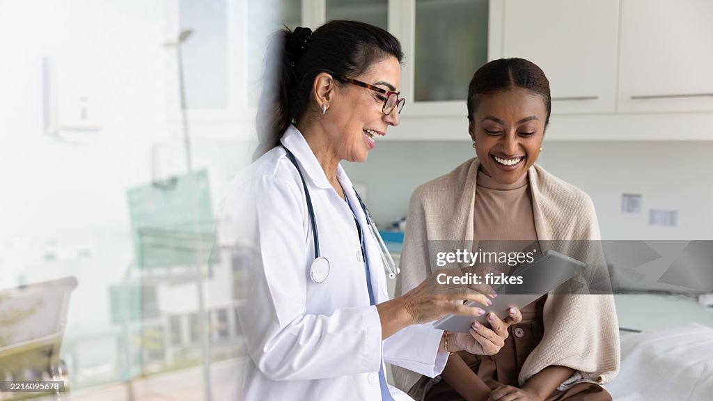 Happy practitioner and African patient watching examination report on tablet