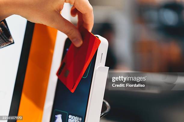 red credit card used for payment at nfc terminal in a store - swiping red card stock pictures, royalty-free photos & images