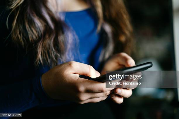 close-up of hands holding a smartphone in casual setting - abuso di minore foto e immagini stock