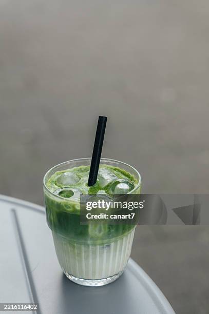 iced matcha latte standing on a table outdoors - matcha stockfoto's en -beelden