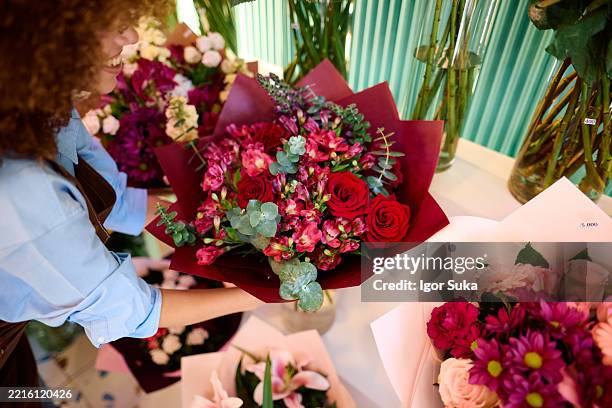 fleuriste préparant un bouquet de roses rouges et d’alstroemeria roses dans un magasin de fleurs - bouquet de fleurs photos et images de collection