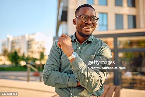 homme d’affaires souriant debout avec les bras croisés dans la ville - représentation masculine photos et images de collection