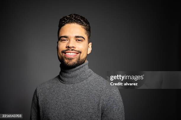 portrait of handsome young hispanic man smiling against gray background - facial hair stock pictures, royalty-free photos & images
