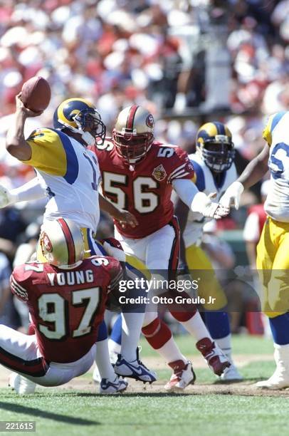 Quarterback Tony Banks of the St. Louis Rams attempts to throw away the football to avoid a sack as defensive lineman Bryant Young of the San...