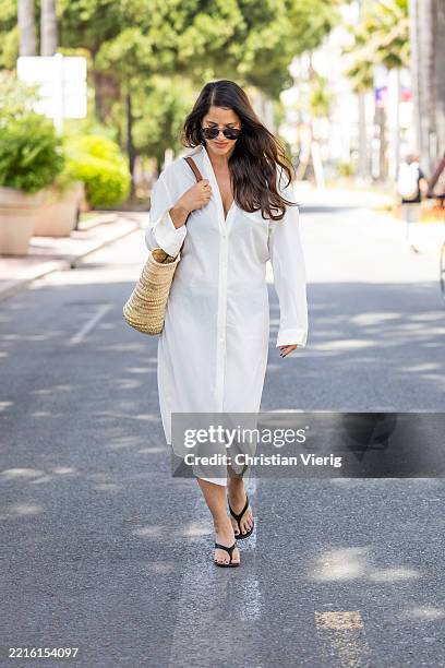 Gili Biegun wears straw Celine bag, white button up dress with long sleeves, sunglasses during day eight of the 78th Cannes Film Festival on May 20,...