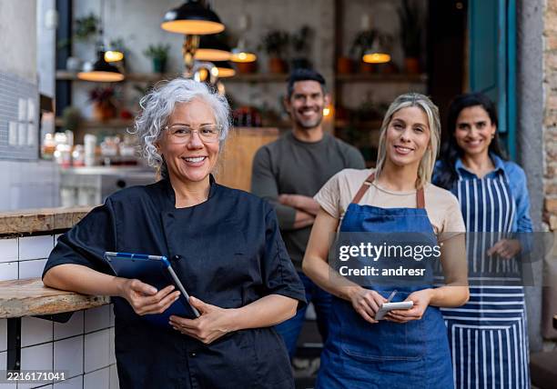 food service employees working at a restaurant and smiling - restaurateur stockfoto's en -beelden