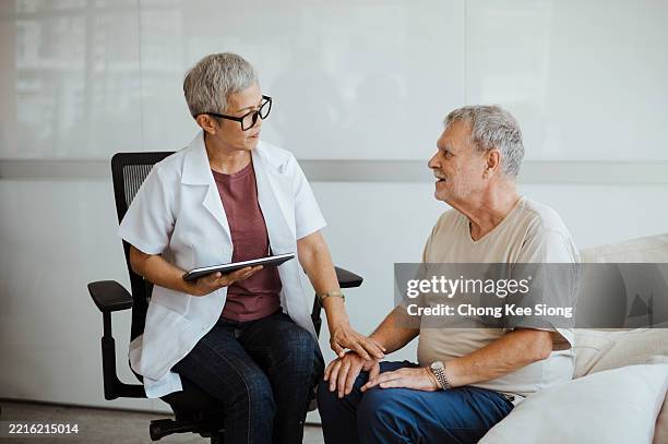 hospice nurse visiting an elderly male patient and comforting patient. - patient bad news stock pictures, royalty-free photos & images