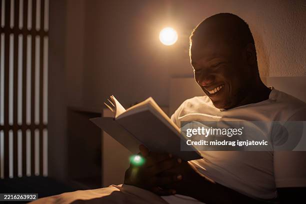 man reading book in bed before sleep - reading before bed stock pictures, royalty-free photos & images