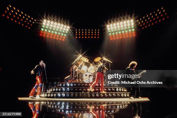 British singer, songwriter and musician Freddie Mercury, wearing a black leather jacket and red leather trousers, British bass guitarist and...