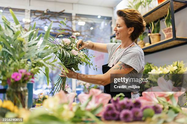 florist arrangiert einen blumenstrauß - blumengeschäft stock-fotos und bilder