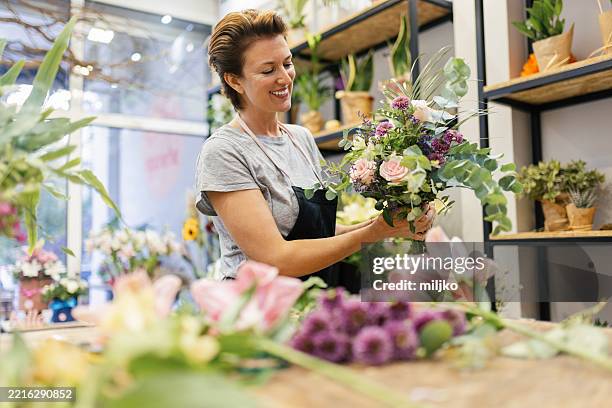 florist in her flower shop - alleen één oudere vrouw stockfoto's en -beelden