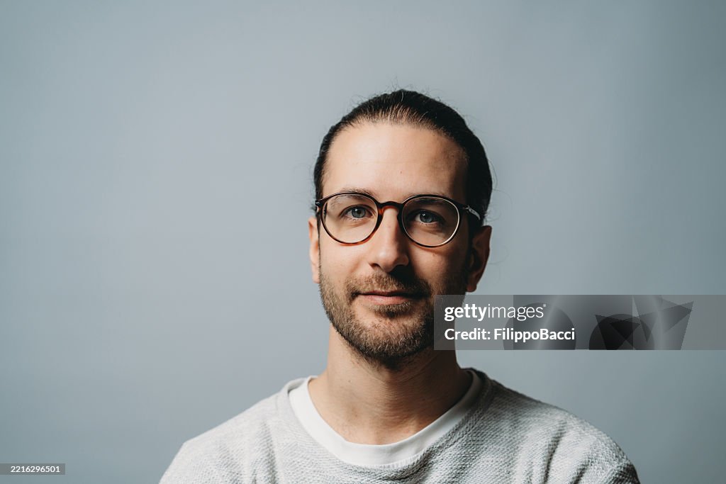 Portrait of a smiling young man with glasses and man bun