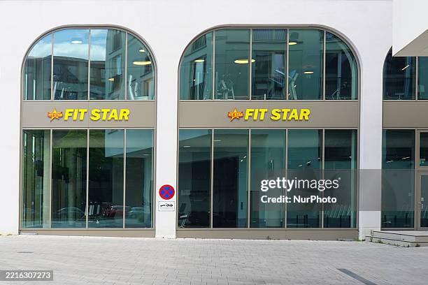 The exterior view of a FIT STAR fitness center features large arched windows and yellow signage in Munich, Bavaria, Upper Bavaria, Germany, on May...