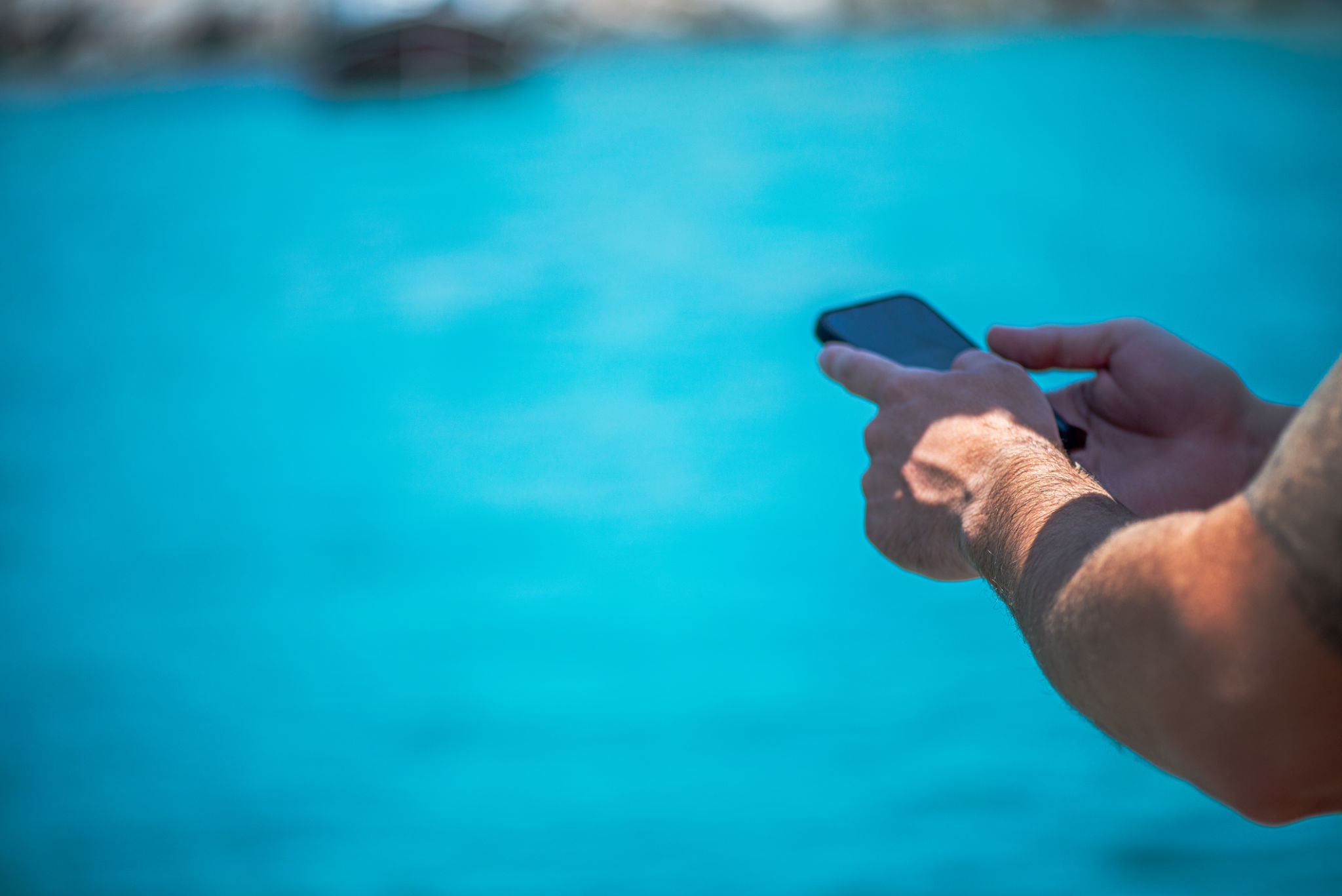 Connected at Sea: Mobile Phone in Hand Over Blue Ocean Connected at Sea: Mobile Phone in Hand Over Blue Ocean